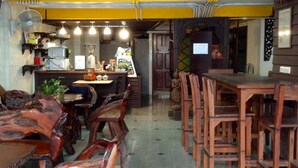 A restaurant interior with wooden furniture, a counter, and a fan. - BC guesthouse Banglamphu (Bangkok)