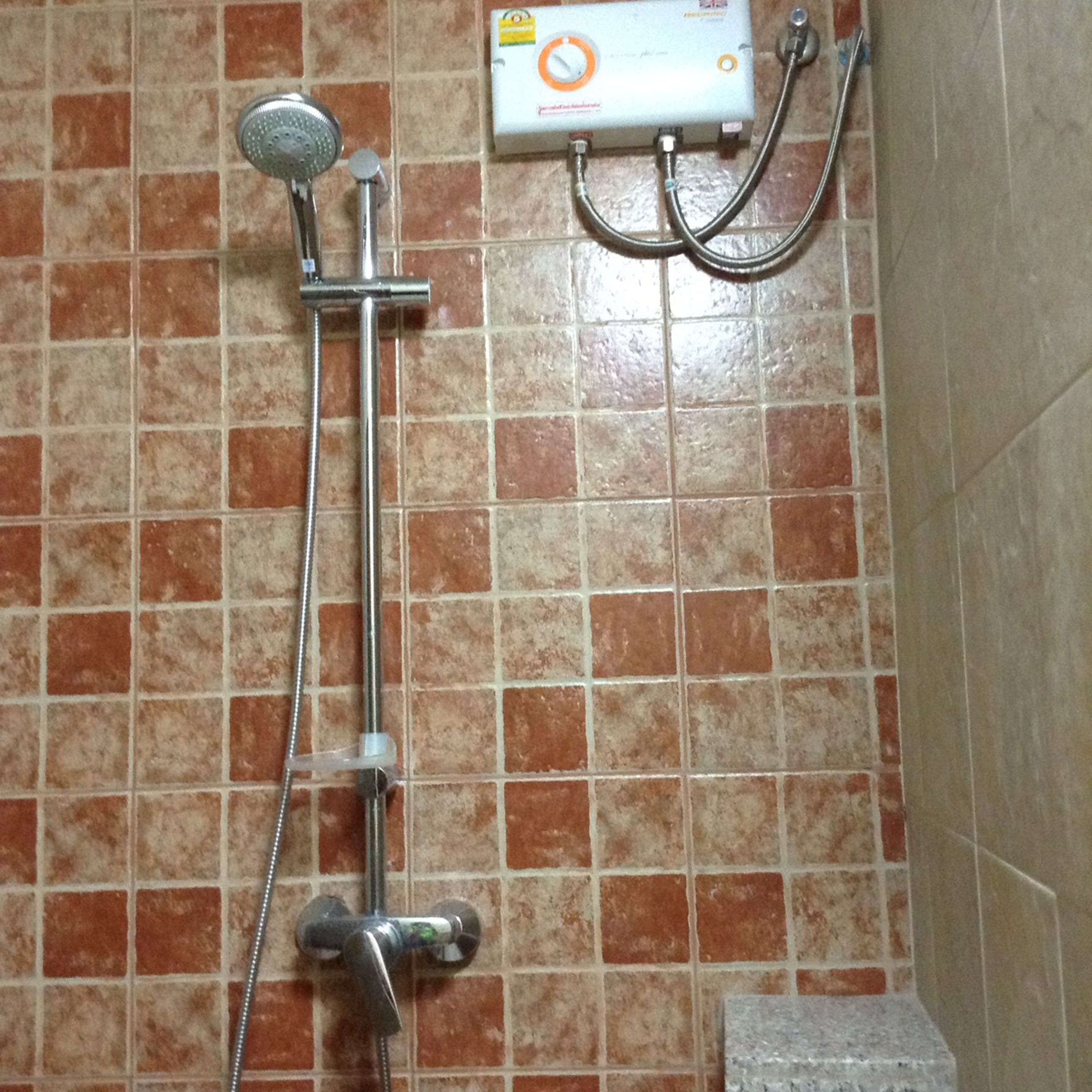 Ducha con cabezal de ducha manual y panel de control en la pared.