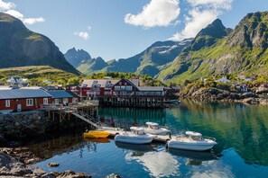 Un pueblo costero con casas tradicionales rojas, un muelle y barcos amarrados en el puerto.