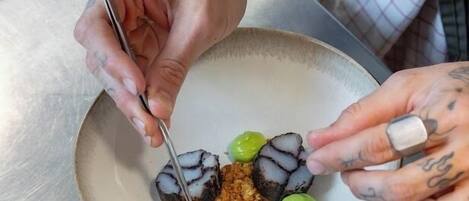 A person with tattoos preparing food on a plate.
