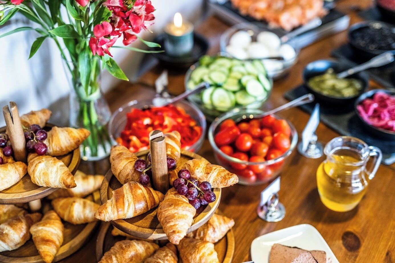 A table with various food items including croissants, grapes, and bowls of vegetables.