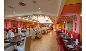 Un restaurante espacioso con techos altos, varias zonas de comedor y una variedad de opciones de asiento, incluyendo cabinas y mesas.