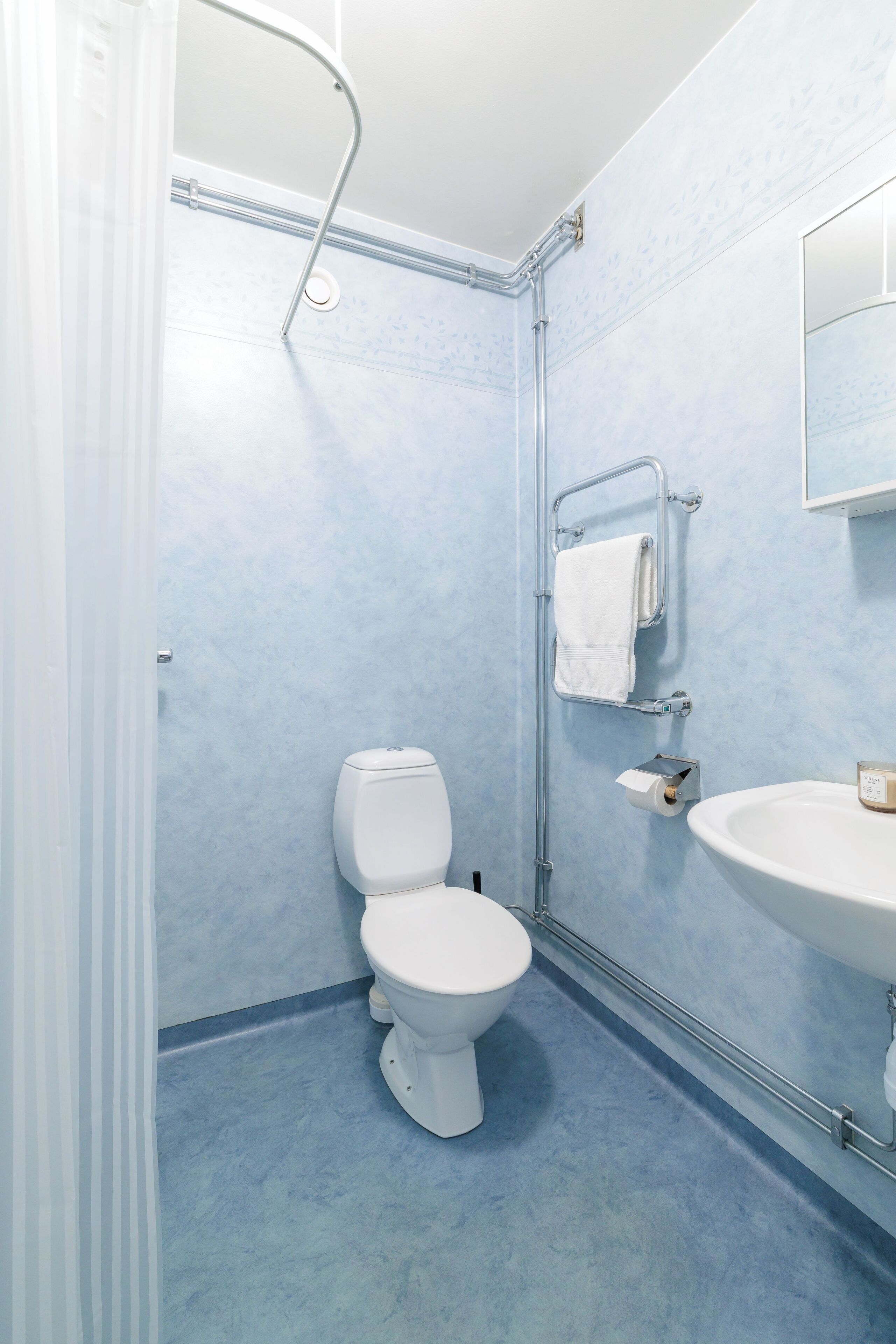 Un bany amb un vàter blanc, un lavabo i una barra de tovalloles.