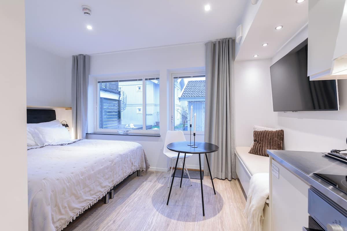 Ein modernes Hotelzimmer mit einem Bett, einem kleinen Tisch, einem Fernseher und einem Schreibtisch.