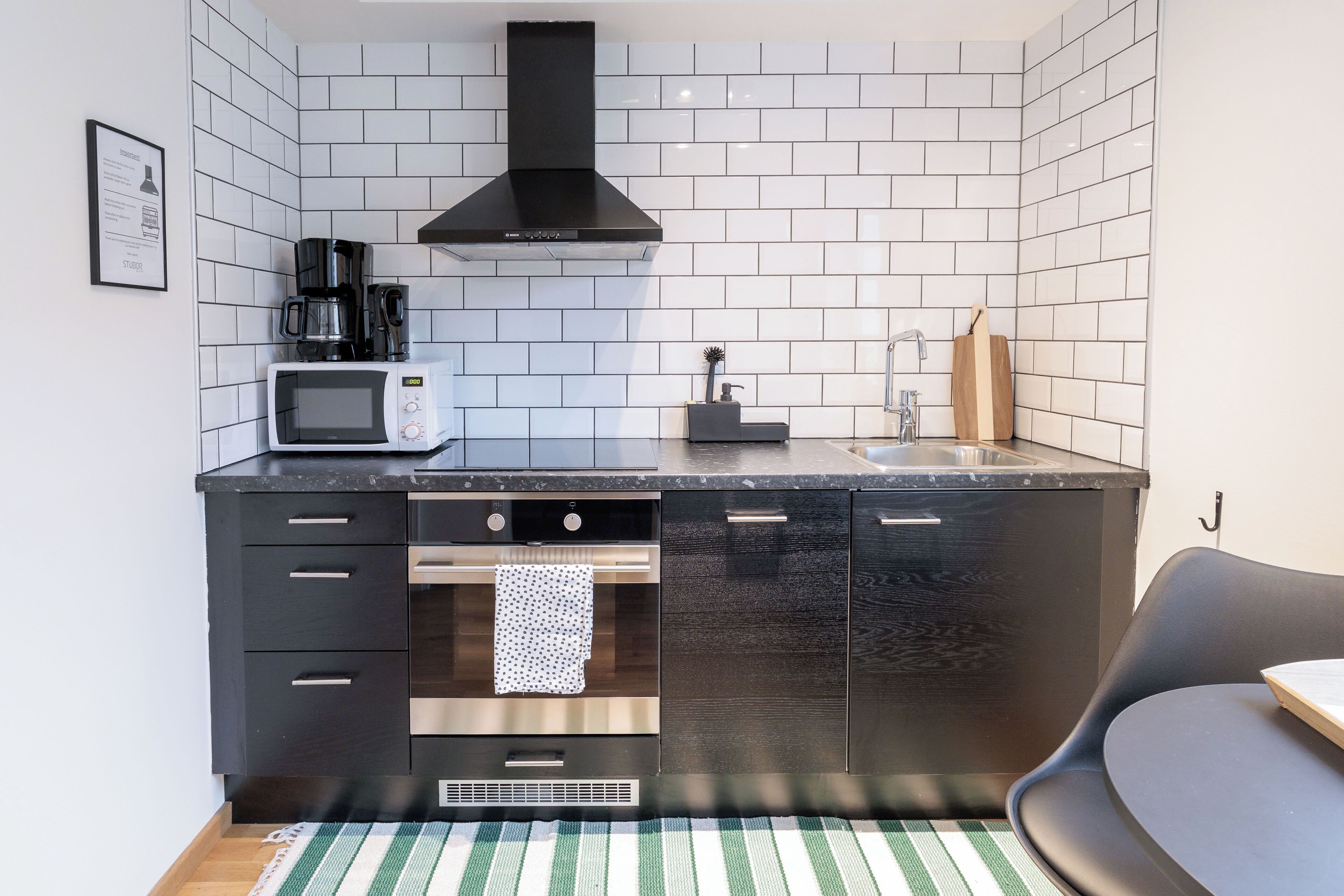 A compact kitchen with a microwave, coffee maker, and a black range hood.