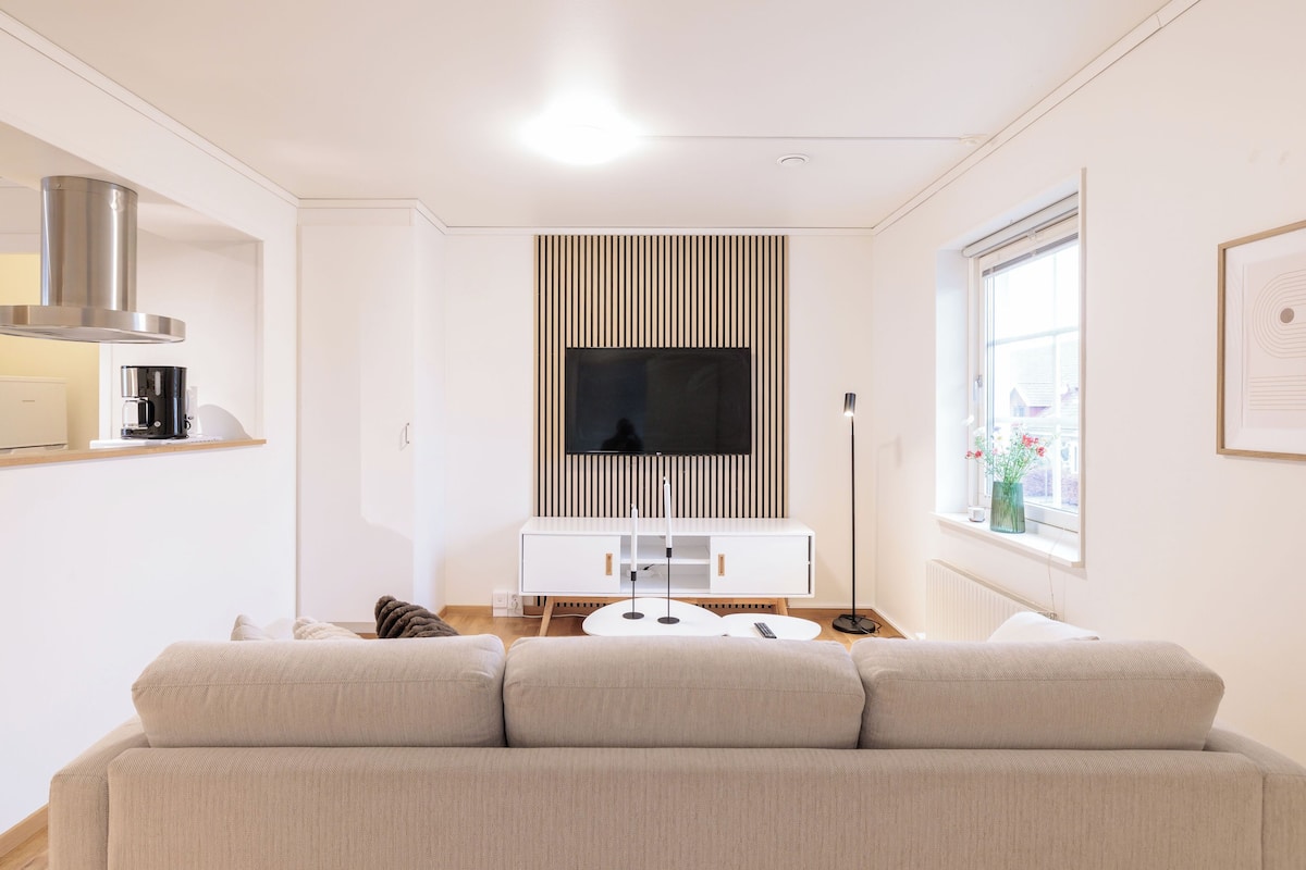 Ein modernes Wohnzimmer mit einer Couch, einer Kaffeemaschine, einem Fernseher und einem Fenster mit Blick.
