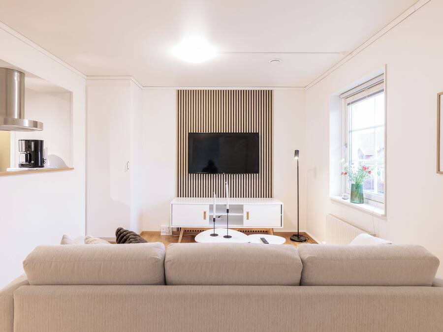 Una sala de estar moderna con sofá, cafetera, televisor y ventana con vista.