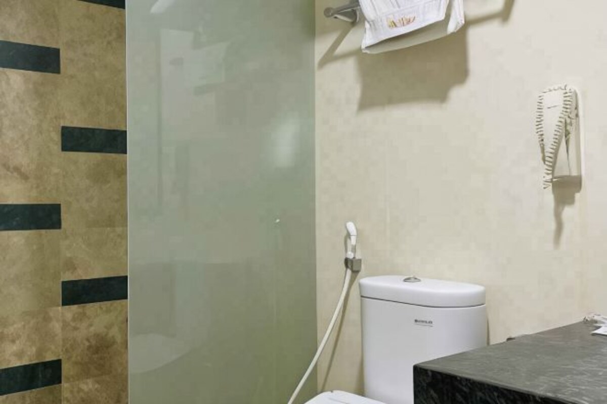 Une salle de bain équipée de toilettes, d’un sèche-mains et d’un porte-serviettes.