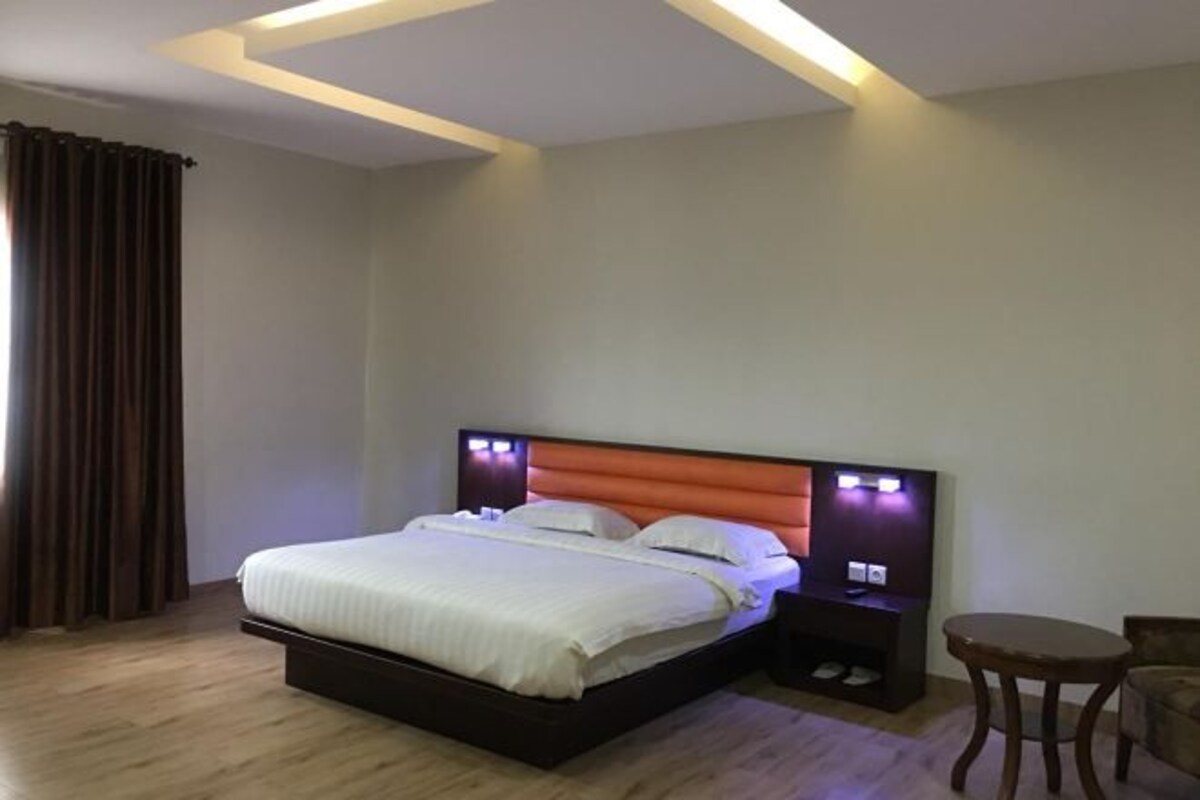 Une chambre d’hôtel avec un lit, une table de chevet, un téléviseur et une chaise.