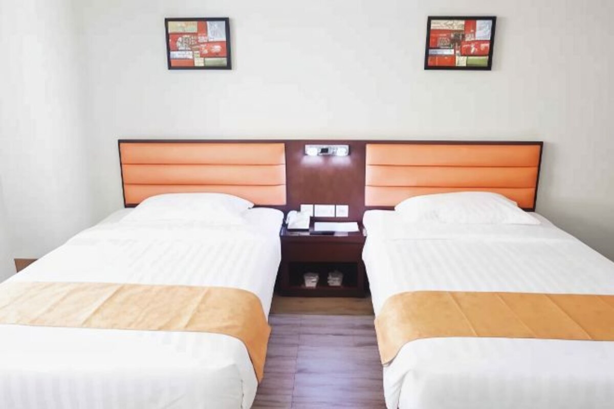 Une chambre double avec deux lits, une table de chevet et une petite table avec une lampe.