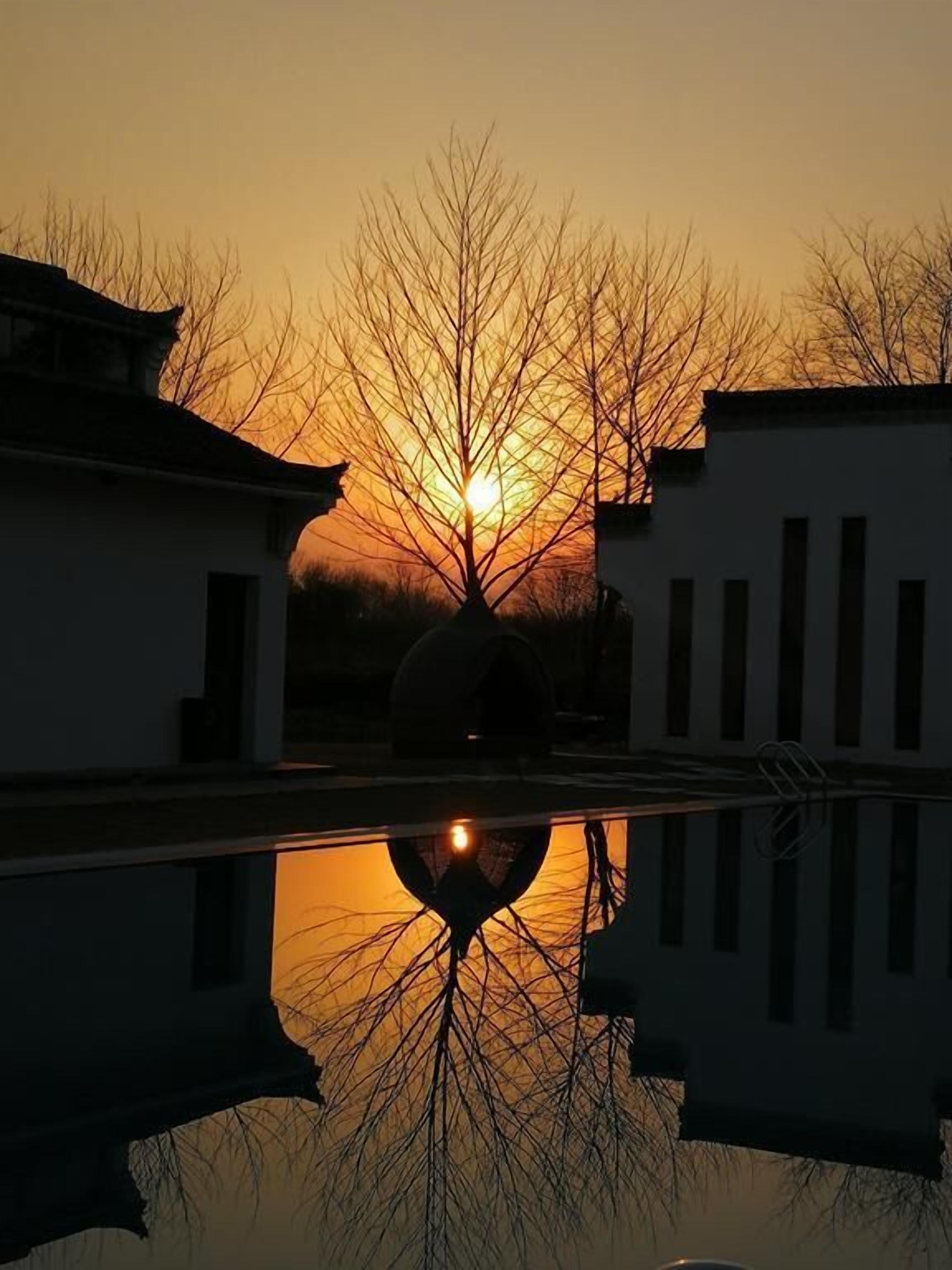A serene sunset over a traditional building with a clear reflection in a still water body.
