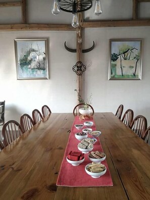 A wooden dining table with a red runner, surrounded by wooden chairs. There are several bowls of food on the table.