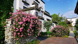 A traditional building with a stone wall and pink flowering bushes. - Huangshan Huizhou Creek Villa (Huangshan)