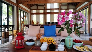 A wooden interior with a sofa, pillows, a tray of food, and a vase of flowers. - Huangshan Huizhou Creek Villa (Huangshan)