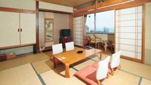 A traditional Japanese room with tatami flooring, a wooden table, chairs, a television, and sliding doors. - Hotel Tetora Resort Tsuruoka (Tsuruoka)