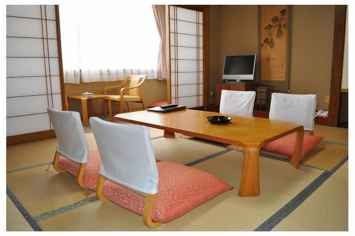 Ett traditionellt japanskt rum med tatamimattor på golvet, ett lågt träbord och shojiskärmar.
