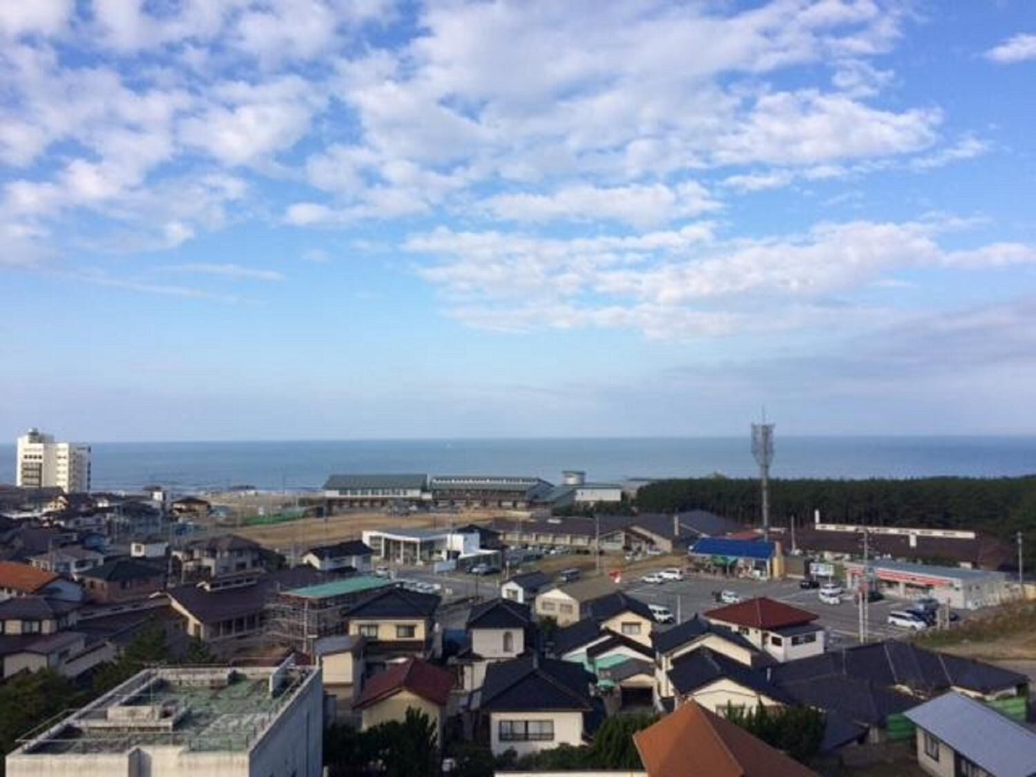 A coastal town with residential buildings, a gas station, and a view of the sea.