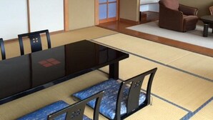 A traditional Japanese-style room with tatami flooring, a low table, and a sofa. - Hotel Tetora Resort Tsuruoka (Tsuruoka)