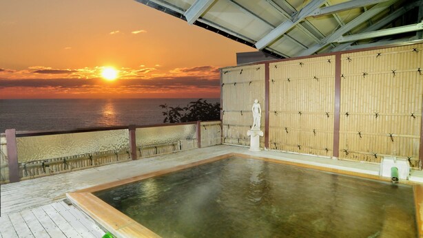 A hot spring area with a view of the sunset over the ocean, a statue, and a bamboo screen. - Hotel Tetora Resort Tsuruoka (Tsuruoka)