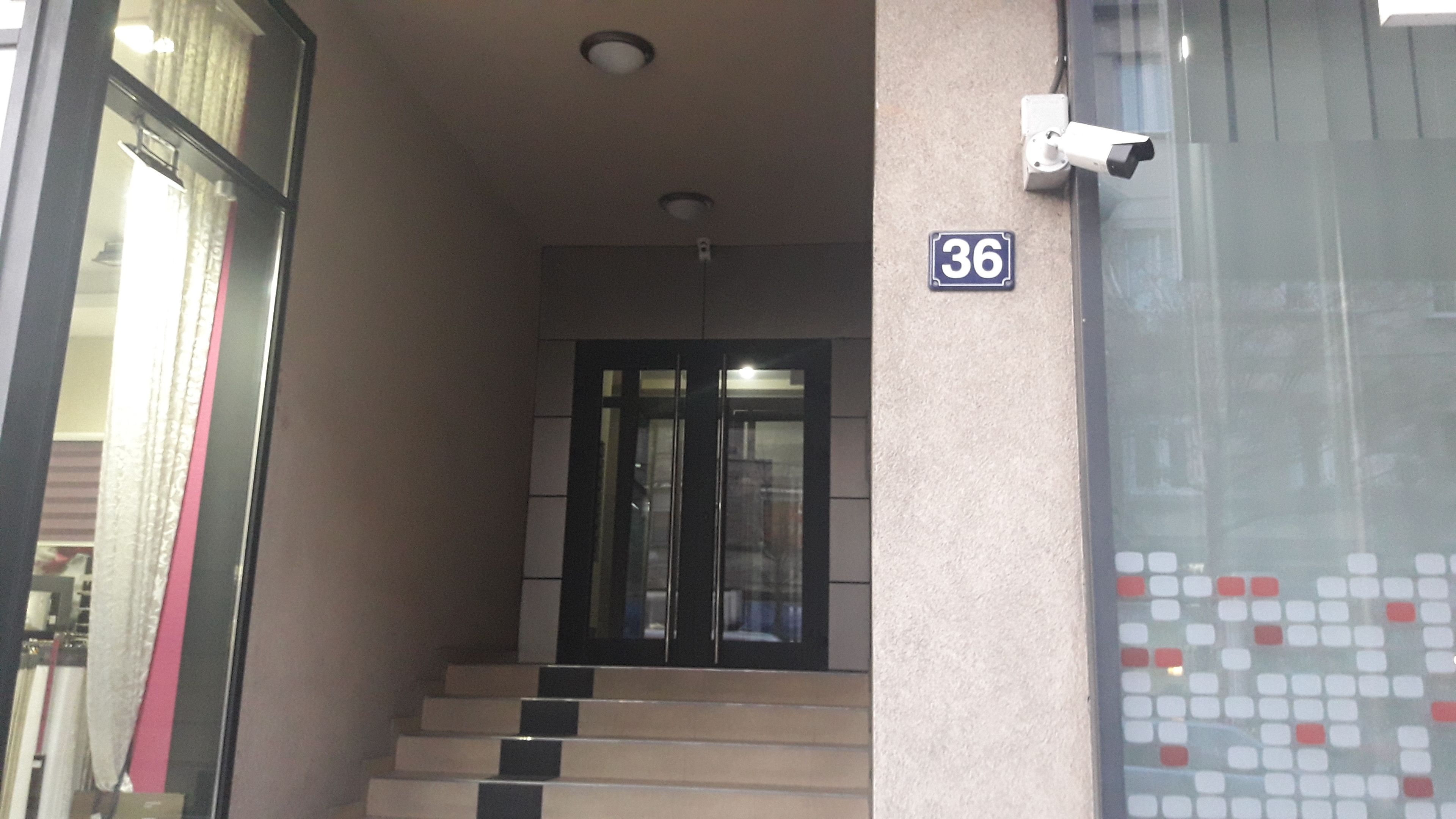 A building entrance with a glass door, a staircase, and a sign indicating the number 36.