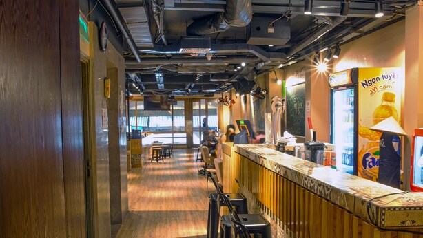 Un restaurant avec un plancher en bois, un bar doté de tabourets et un mur orné de motifs.