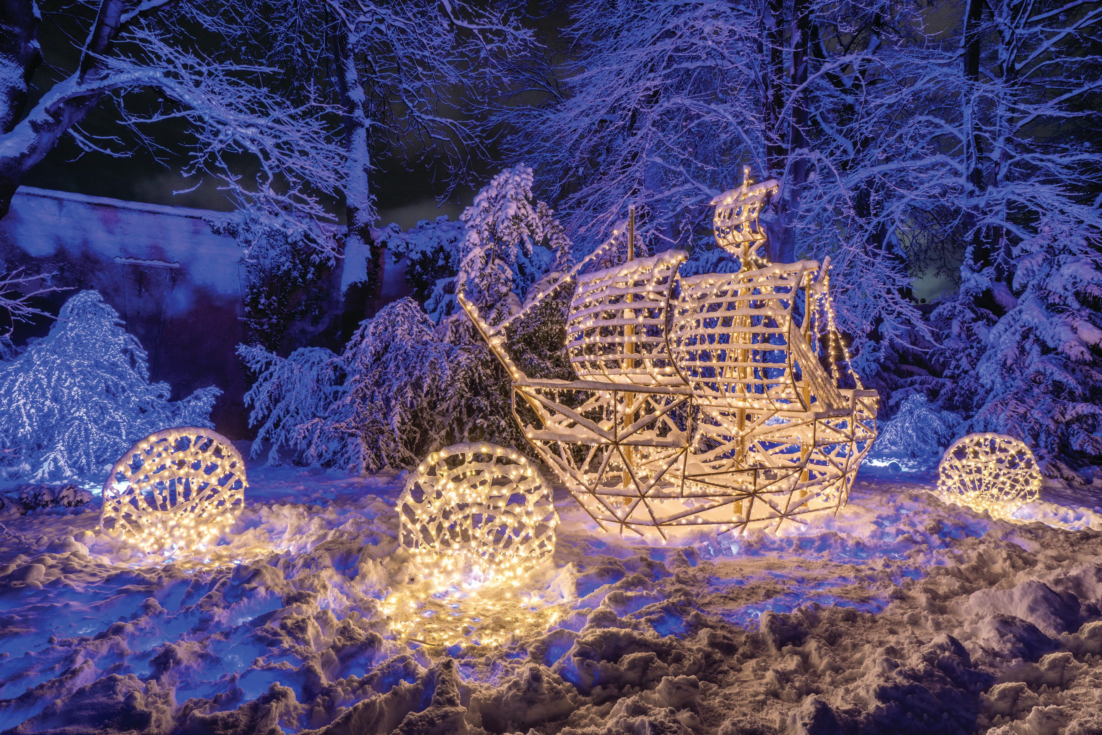 Een besneeuwd landschap met verlichte structuren die op een schip en bolvormige decoraties lijken.