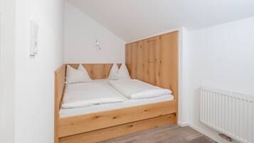 A bedroom with a wooden bed frame, white bedding, and a white radiator.