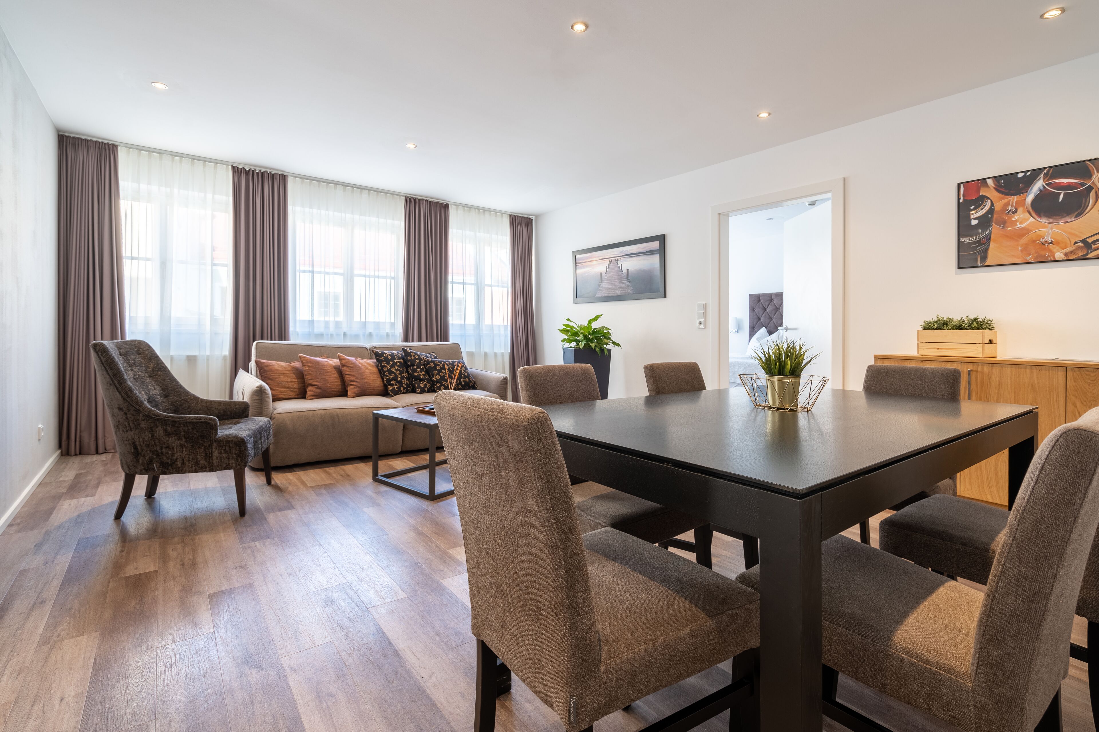 Una sala moderna con sofá, sillones, una mesa de comedor y una zona de cocina.