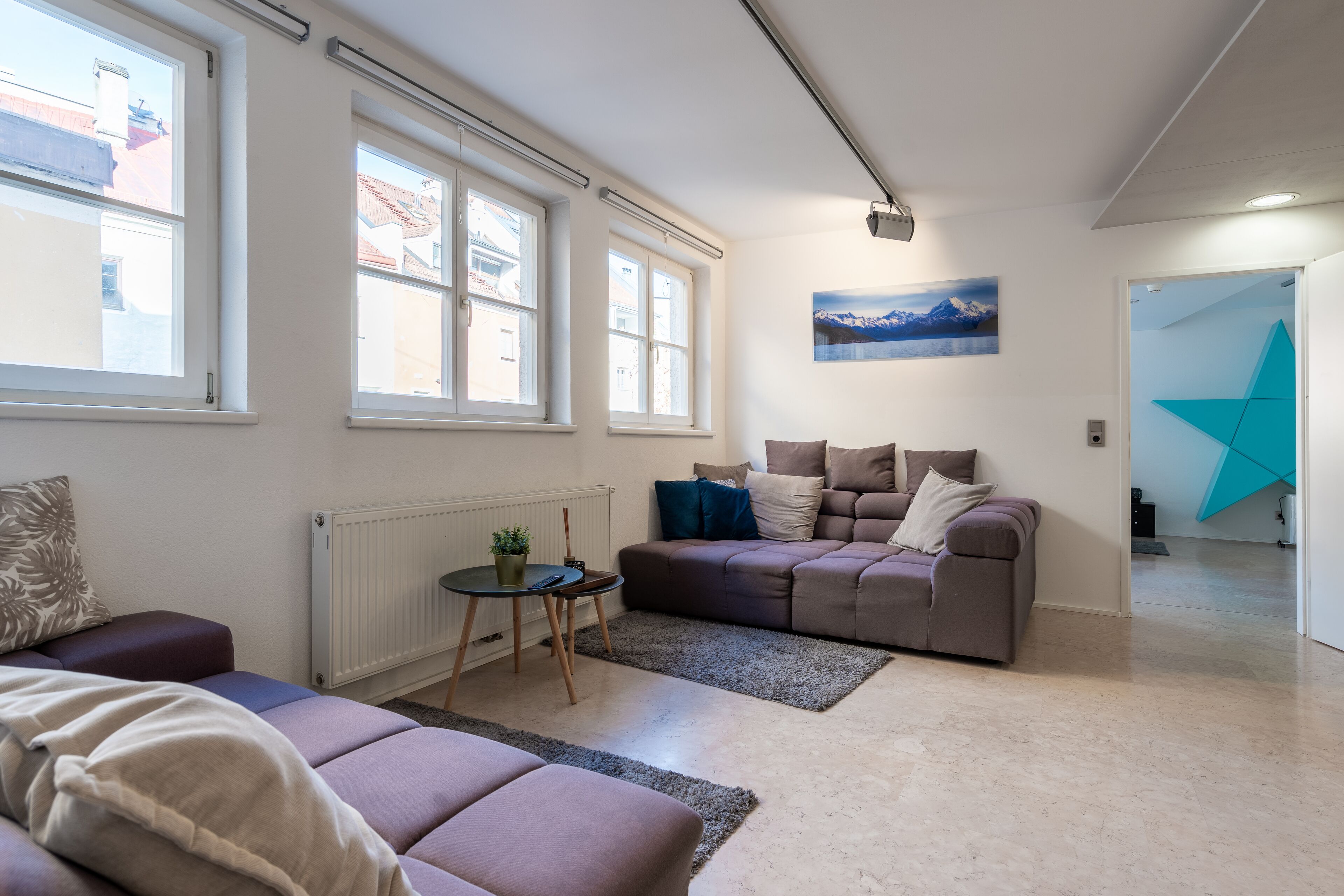 A modern living room with a sofa, a coffee table, and a large window.