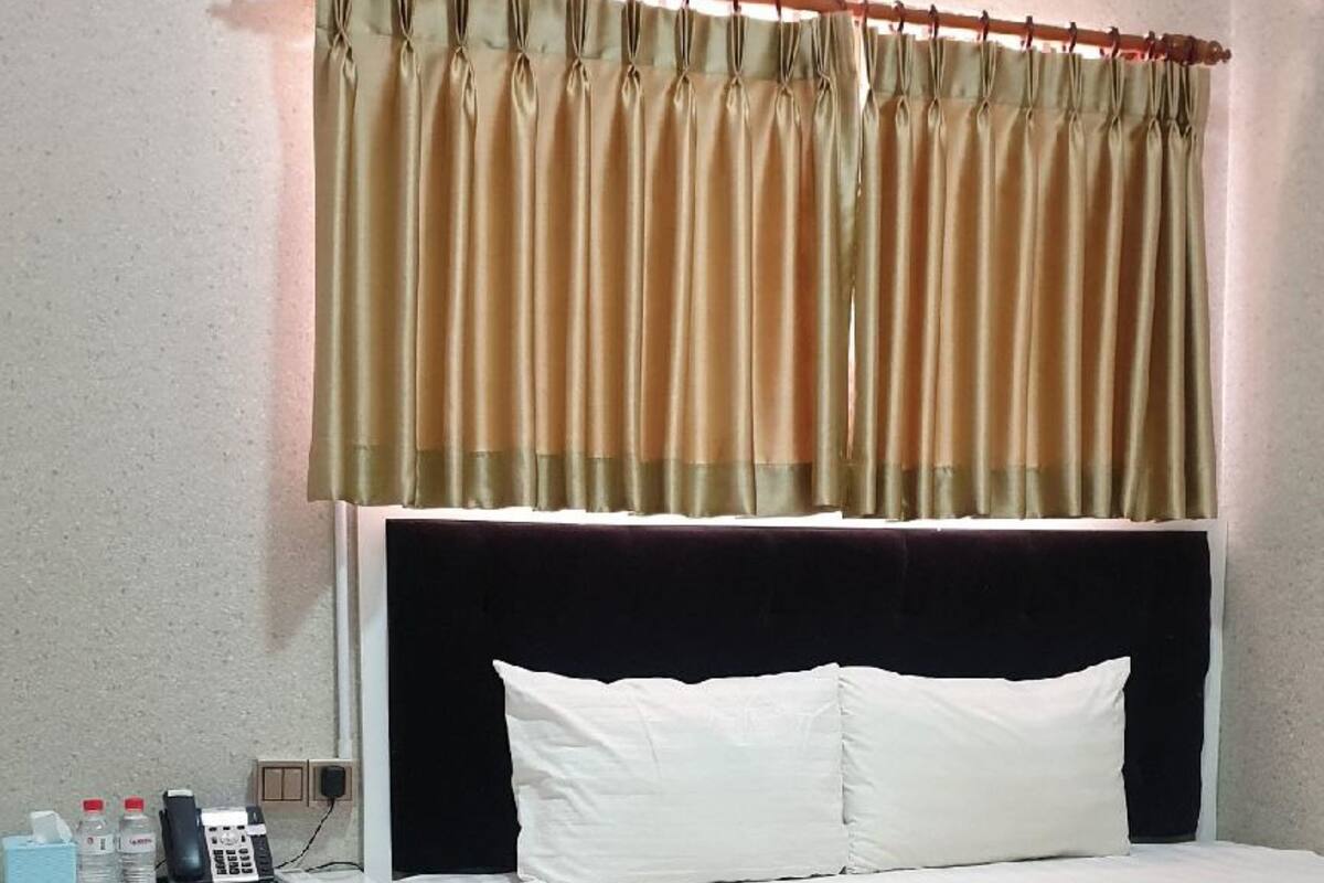 A hotel room with a bed, a nightstand, a telephone, and a lamp.