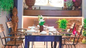 A dining area with a table set for four, surrounded by chairs. A sign above the table reads "SY Luxury House." - SY Guesthouse (Phnom Penh)