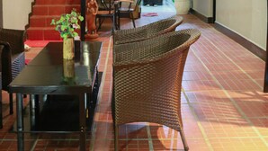 A spacious lobby with a staircase, wicker furniture, a ceiling fan, and a potted plant. - SY Guesthouse (Phnom Penh)