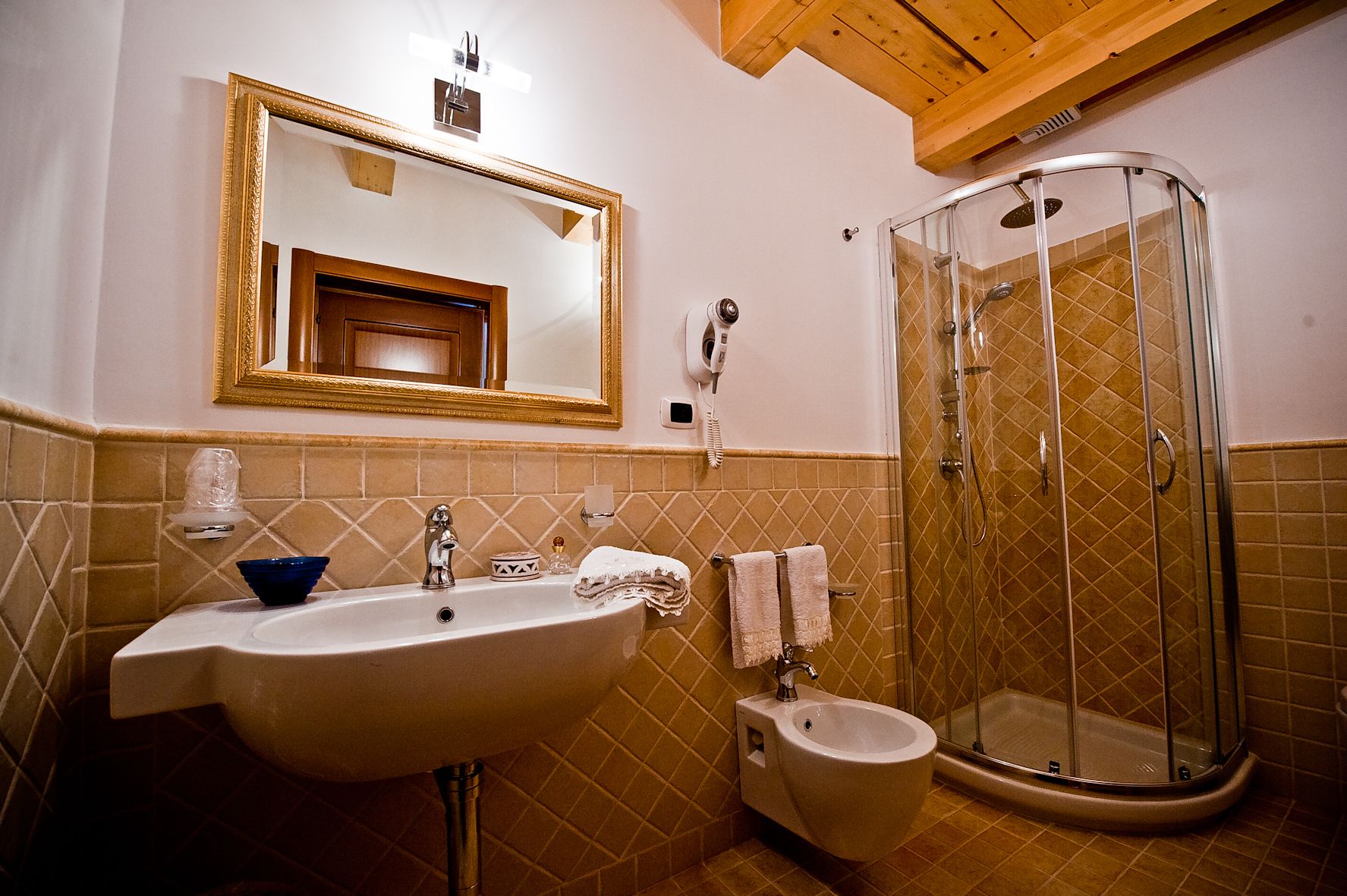 A bathroom with a sink, mirror, bidet, and shower.