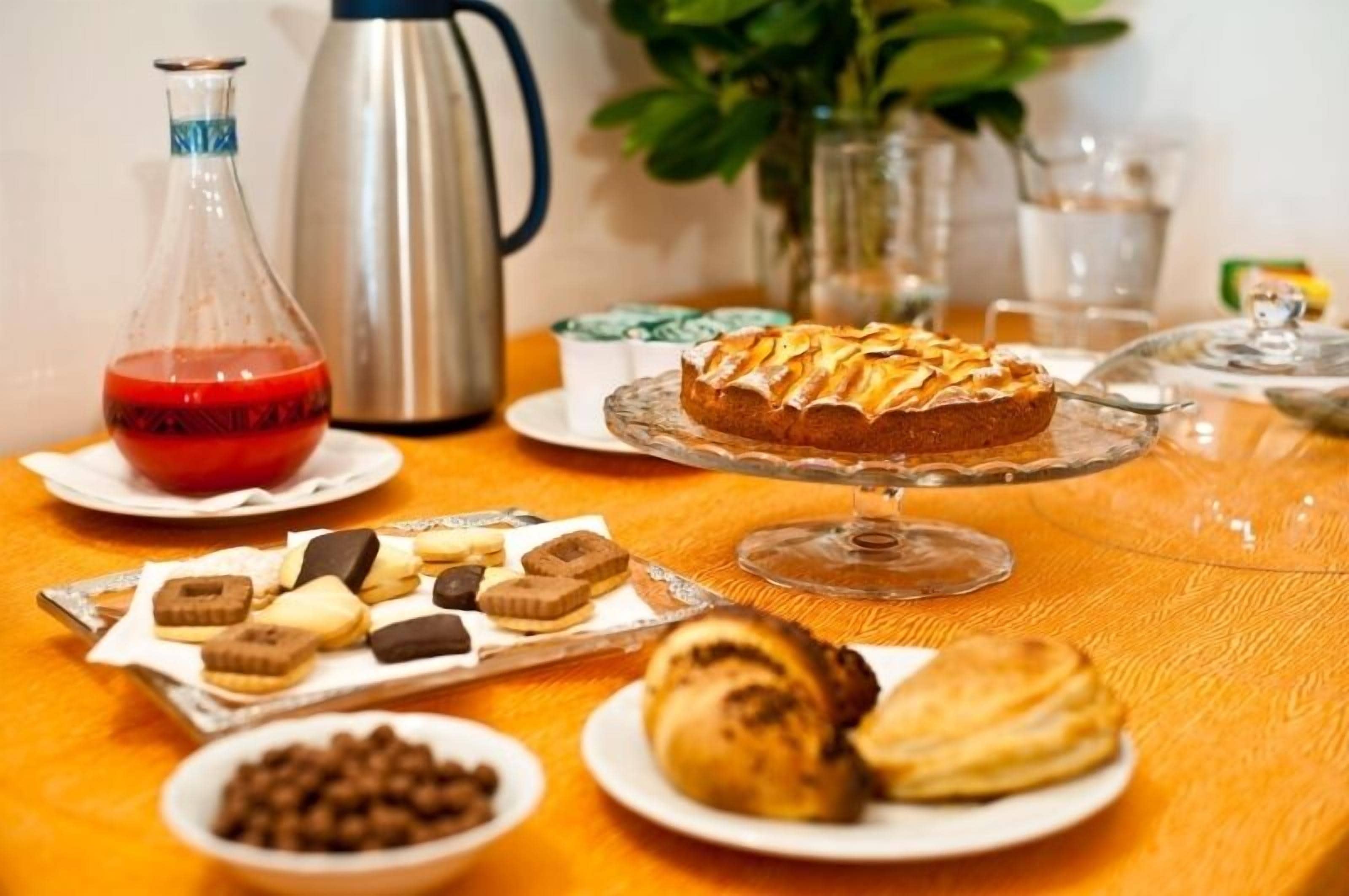 Une table avec des pâtisseries, un gâteau, un thermos et une cafetière.