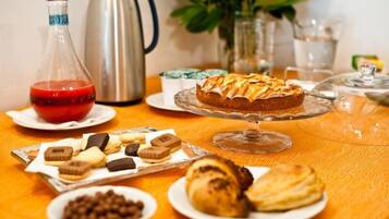 Une table avec des pâtisseries, un gâteau, un thermos et une cafetière.