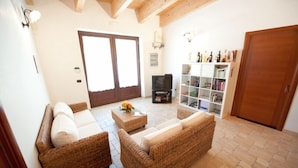 A living room with wicker furniture, a television, and a bookshelf.