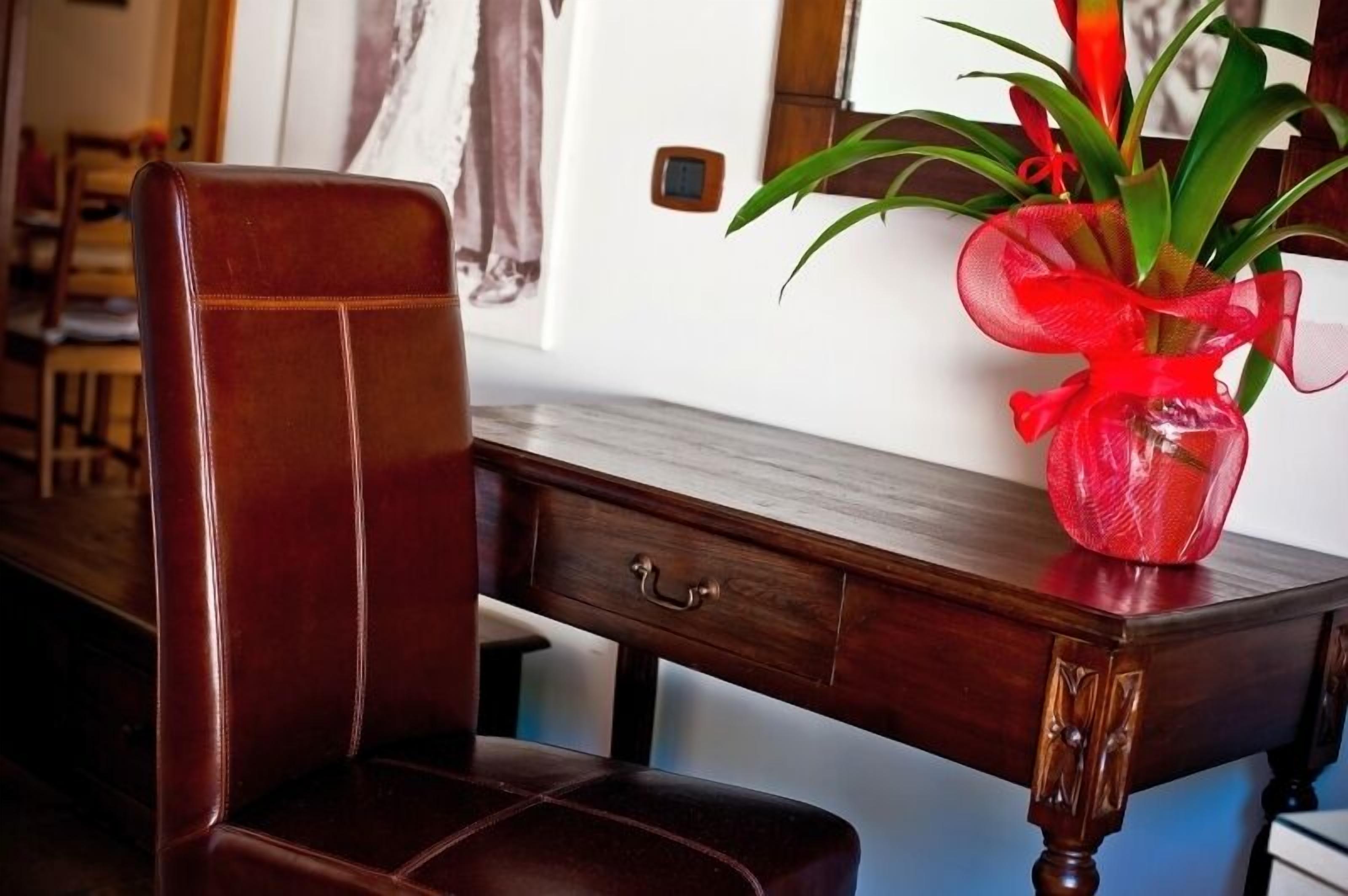 A wooden desk with a vase of flowers and a chair.