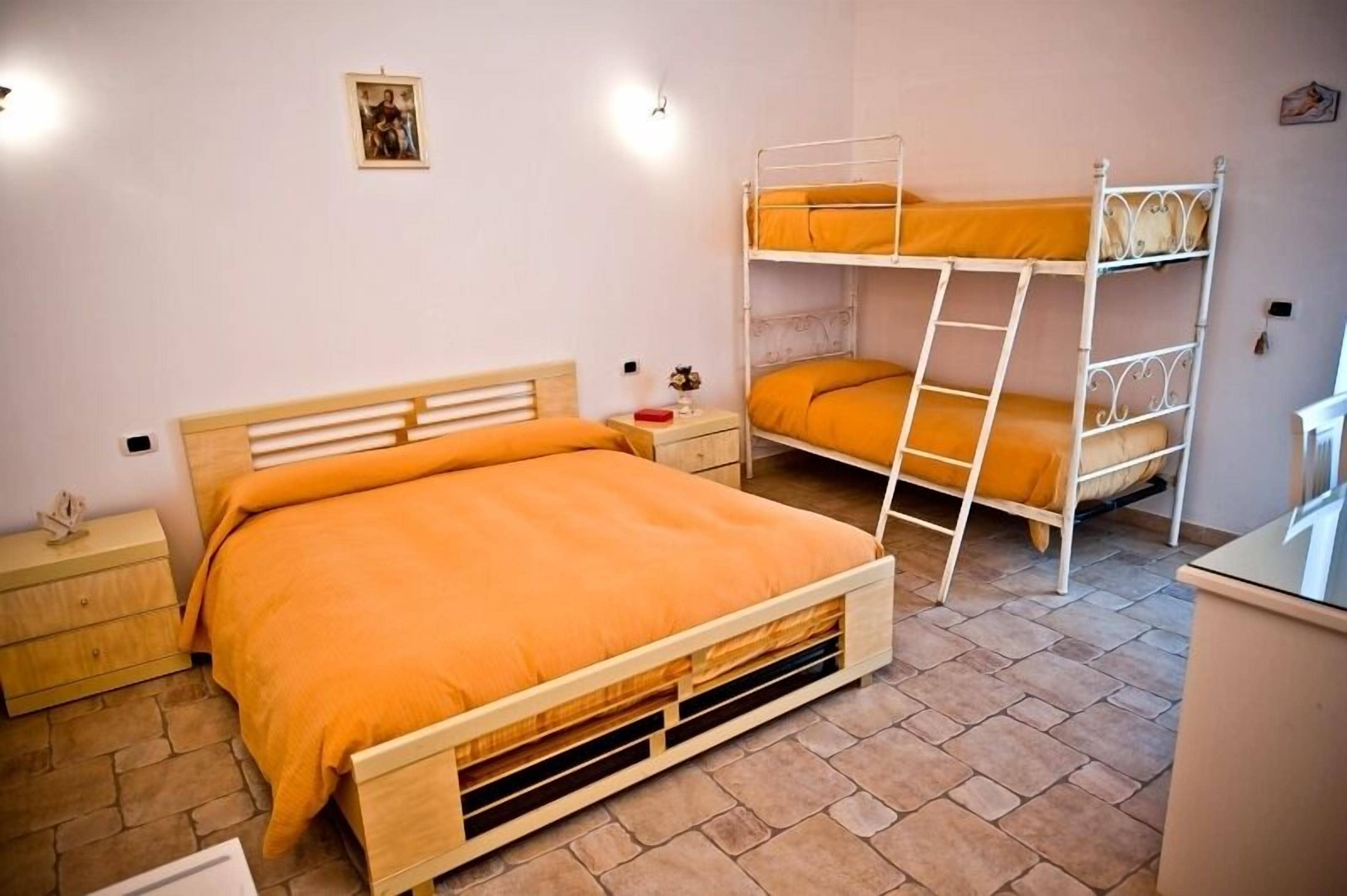 Un dormitorio con una cama de madera, una cama individual superpuesta, una mesita de noche y una pequeña mesa.
