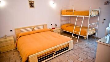 Un dormitorio con una cama de madera, una cama individual superpuesta, una mesita de noche y una pequeña mesa.