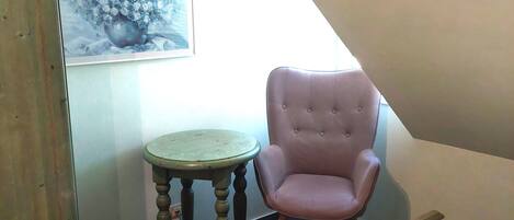 A bedroom with a bed, a chair, a small table, and a cabinet.