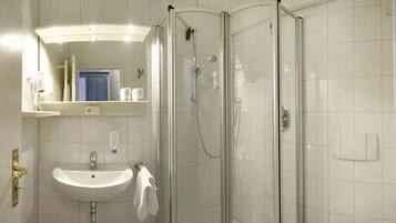 Une salle de bain avec une douche à parois de verre, un lavabo et un miroir au-dessus du lavabo.