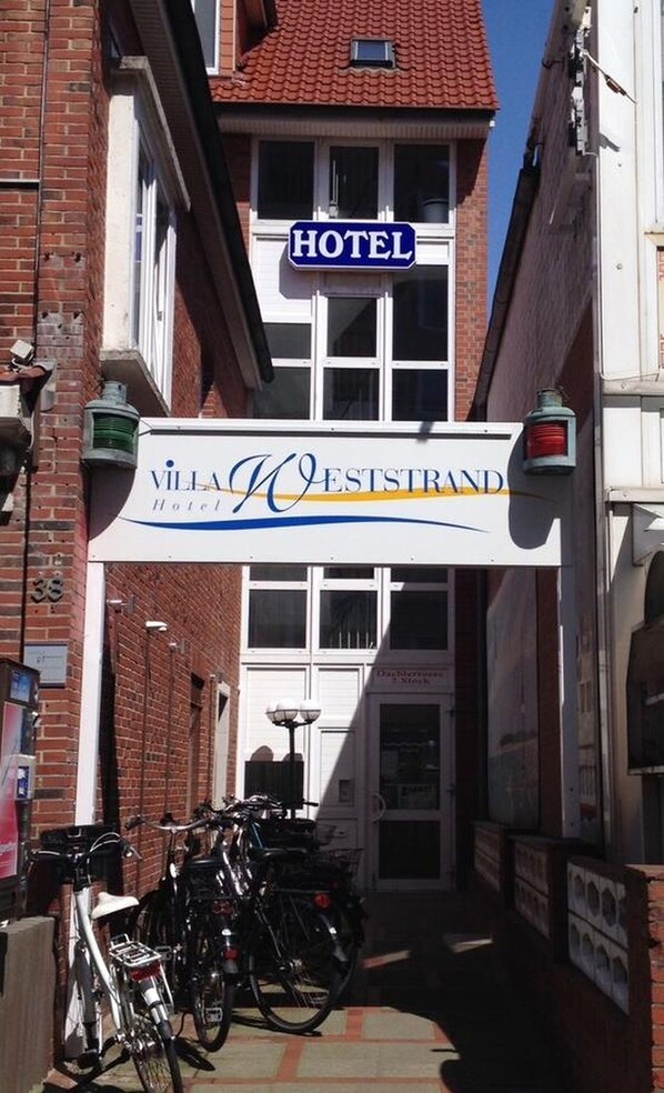 Señal de hotel con techo rojo y un cartel que dice "Villa Weststrand Hotel".