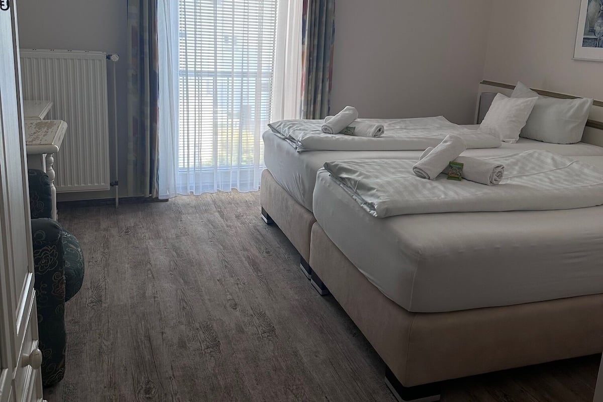 Ein Hotelzimmer mit einem großen Bett, einem Schminktisch und einem Fenster mit Vorhängen.