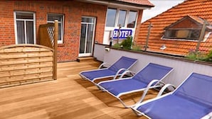 Une terrasse d’hôtel avec une porte en bois, un mur en briques et une enseigne indiquant « HÔTEL ».