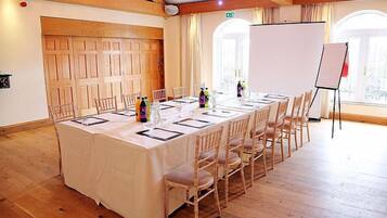 A conference room with a long table, chairs, a whiteboard, and a projector.