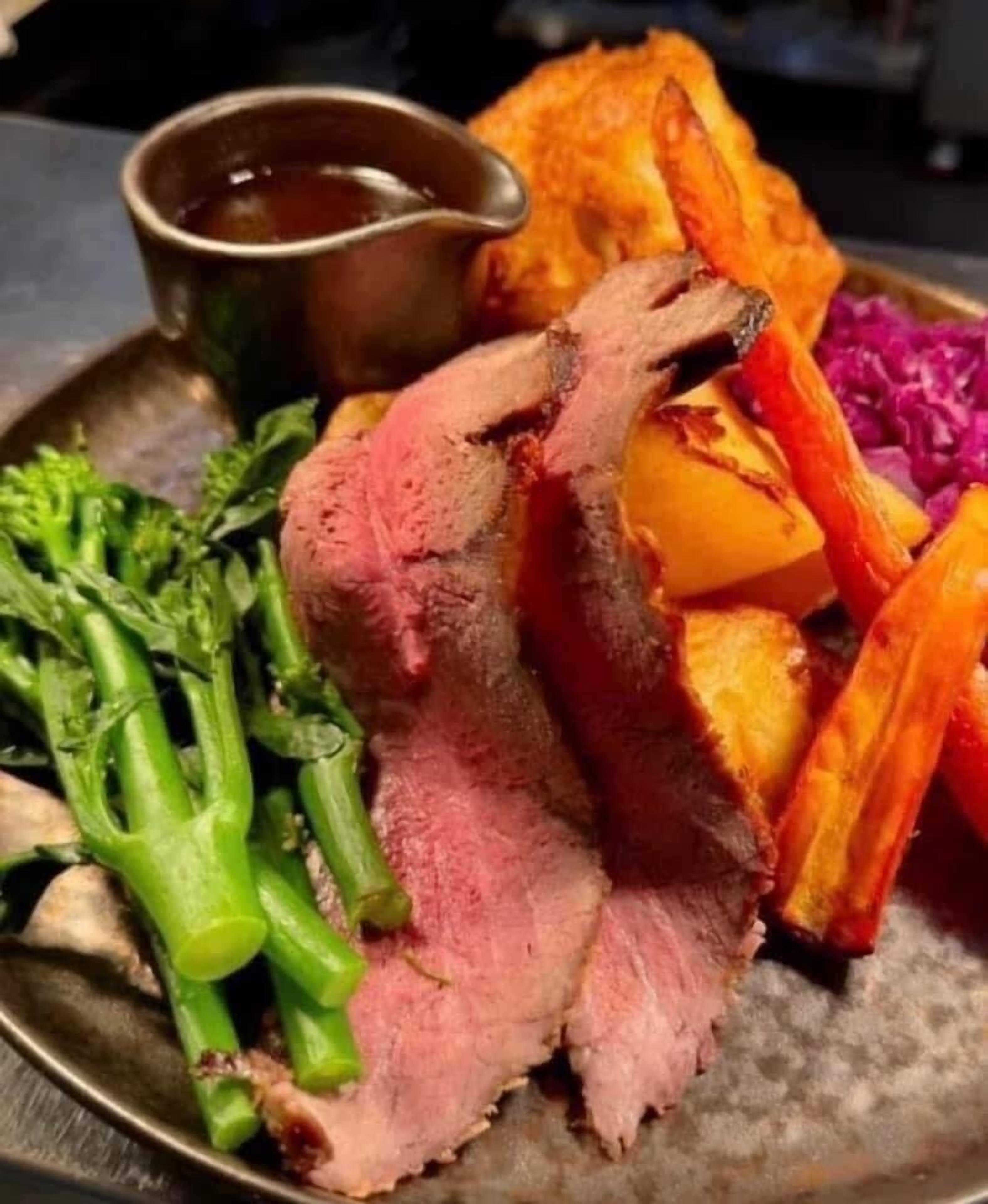 A plate of food with roast beef, roasted potatoes, and green vegetables.