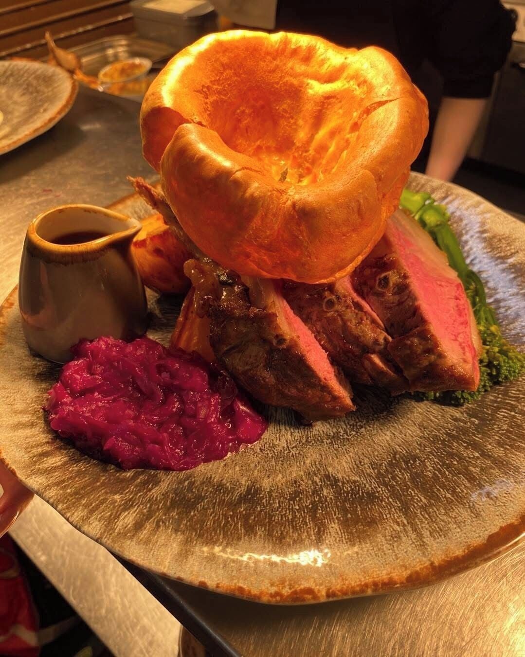 A plate with a Yorkshire pudding, sliced meat, and a side of beetroot.