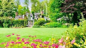 Una casa tradicional rodeada de abundante vegetación y un jardín bien cuidado con diversas flores.