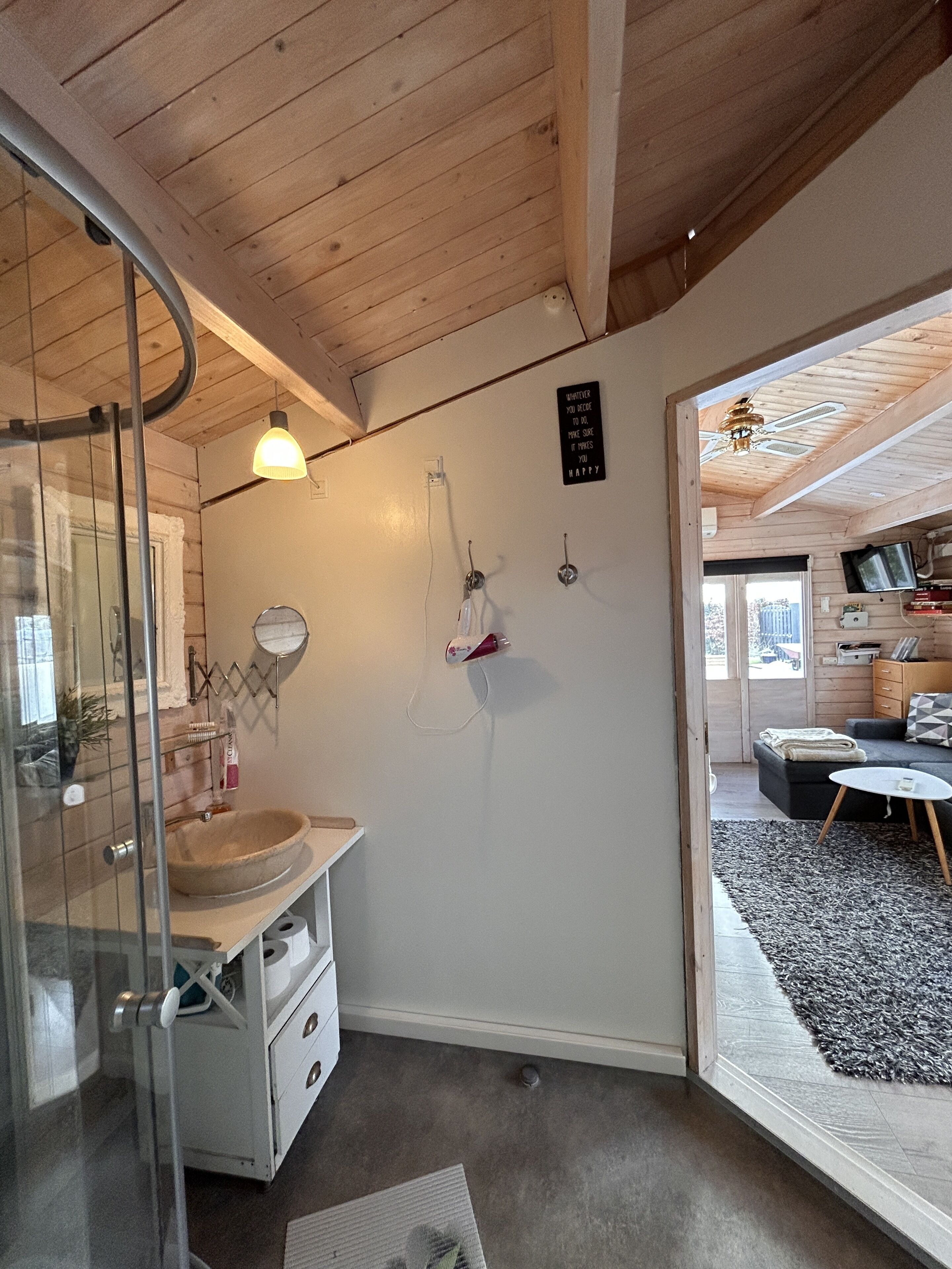 Un baño moderno con cabina de ducha de vidrio, tocador de madera y ventilador de techo.