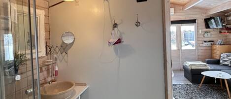 Un baño moderno con cabina de ducha de vidrio, tocador de madera y ventilador de techo.